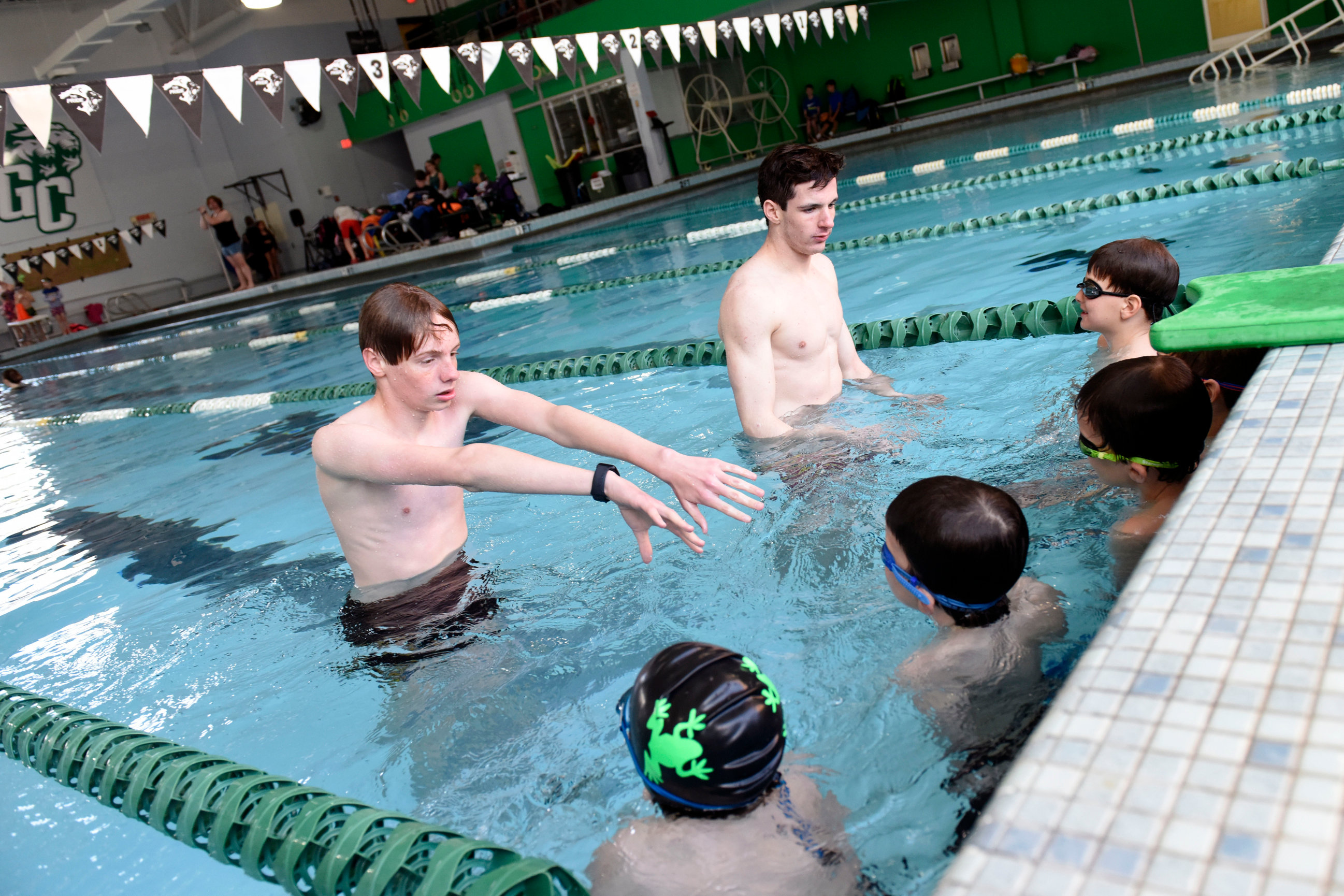 Photo of Friendly swim team junior coaches Colin Auer and Adam Stephany assisting young swimmers in 2025 preseason swim warmups.